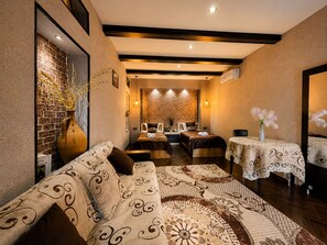 A hotel room with a sofa, a bed, a table with a lace tablecloth, and a brick wall. - Sheki Secret Garden (Sheki)