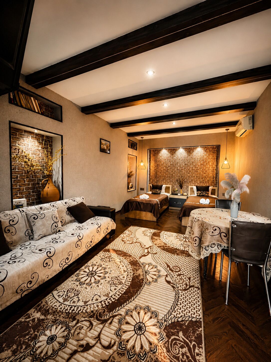 Une chambre d’hôtel confortable avec un canapé, une table à manger et un tapis à motifs.