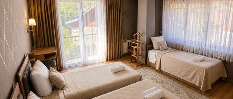 A hotel room with two beds, a desk, a chair, and a view of the outdoors.