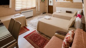 Une chambre d’hôtel avec deux lits, une table à manger, un téléviseur et une fenêtre avec des stores.
