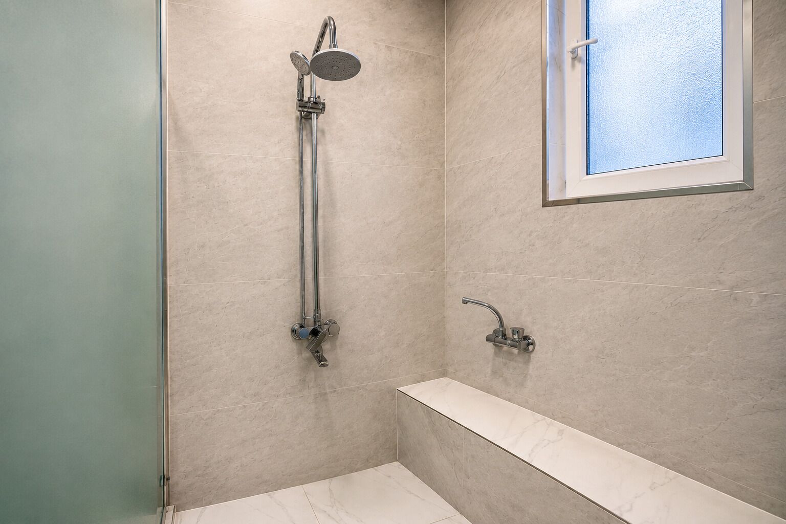 Une salle de bain avec une douche, une baignoire et une fenêtre.