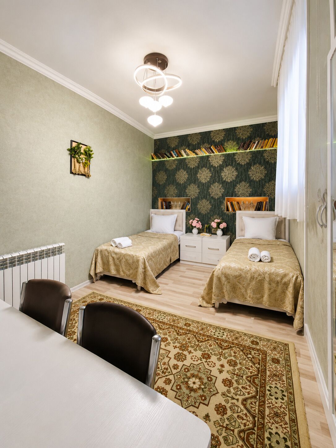 Hotellihuone, jossa on kaksi sänkyä, ruokailutila, patteri ja kuviollinen matto.