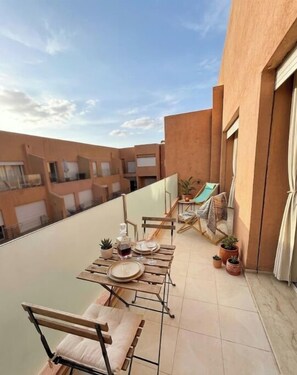 Ein Balkon mit Esstisch, Kübelpflanzen und einer Hängematte.
