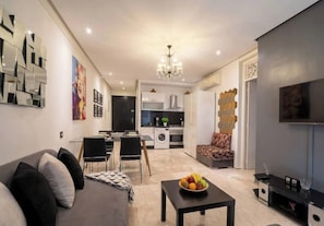 Ein modernes Wohnzimmer mit einer Couch, einem Esstisch und einer Küche im Hintergrund.