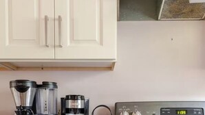 Een keuken met een fornuis, een koffiezetapparaat en een waterkoker.