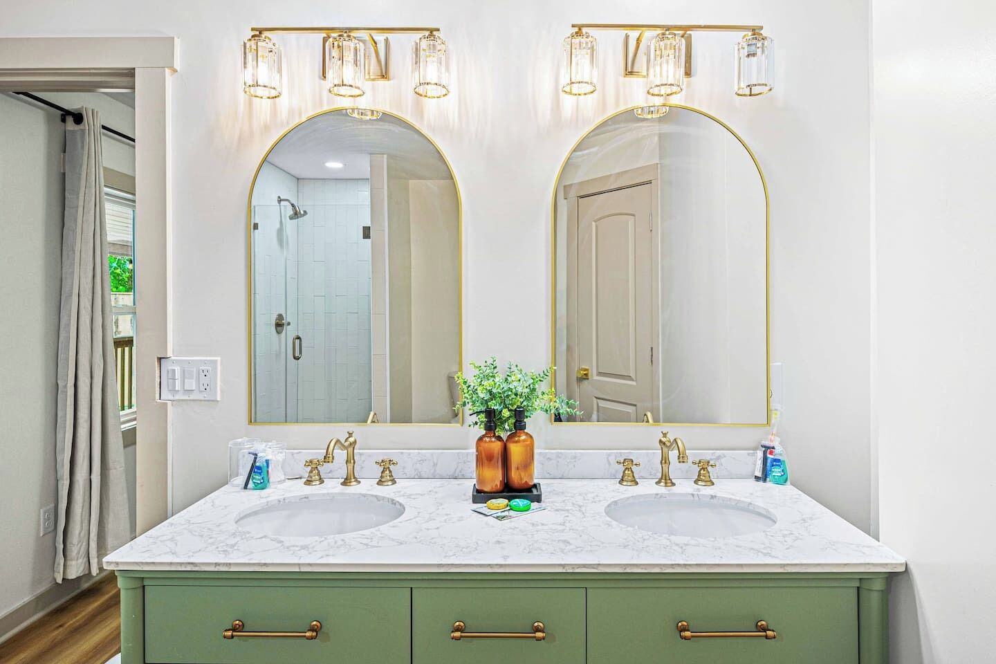 A bathroom with two sinks, a large mirror, and a green vanity with drawers.