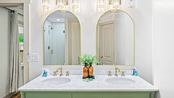 A bathroom with two sinks, a large mirror, and a green vanity with drawers.