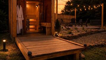 Eine Holzhütte mit Terrasse, Sauna und Lichterkette.
