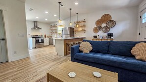 A modern kitchen with a central island, wooden flooring, and a blue sofa with decorative pillows. - Double PCB Oasis: Pool/ 2 Hot Tubs/ Arcades/ 2 Golf Carts
Unit A & B Combined (Panama City)