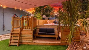 A wooden playhouse with a bench and a ladder, surrounded by a grassy area and a wooden fence. - Double PCB Oasis: Pool/ 2 Hot Tubs/ Arcades/ 2 Golf Carts
Unit A & B Combined (Panama City)