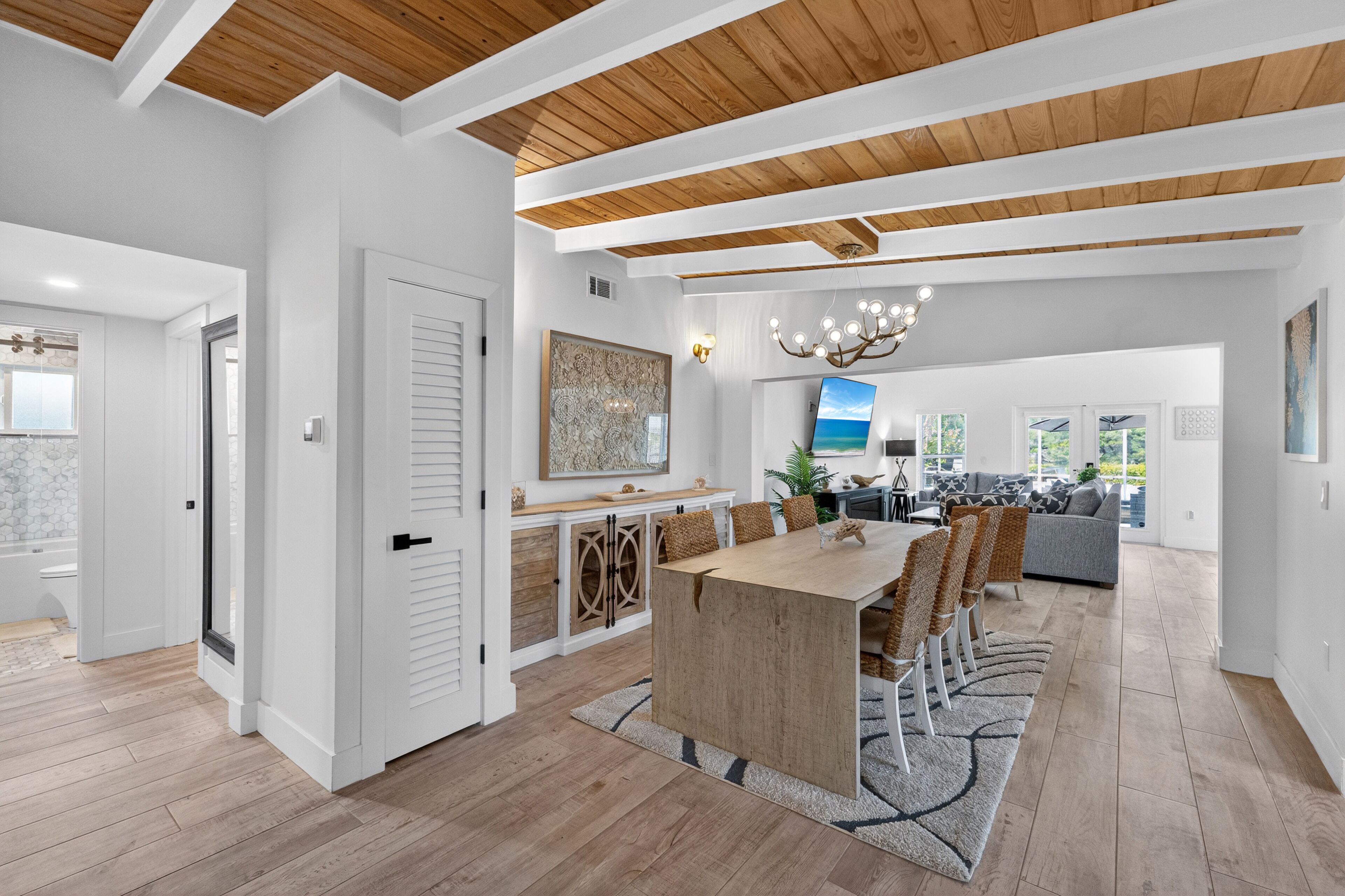 A spacious kitchen with a large island, wooden ceiling beams, and a view into the dining area.