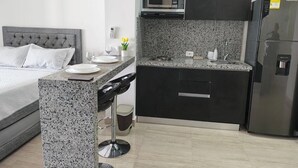 A modern kitchen with a built-in microwave, a refrigerator, and a granite countertop. - MODERNA APARTA-SUITE CON VISTA AL LAGO (cartagena)