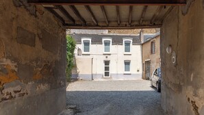 A narrow alleyway leading to a building with a row of windows and a car parked outside.