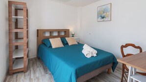 A bedroom with a bed, a wooden ladder, a desk, and a chair.