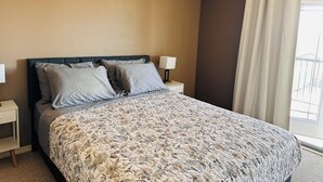 A bedroom with a bed, two bedside tables, a window with curtains, and a view outside. - Modern Duplex with 3 bedroom (Dawson Creek)