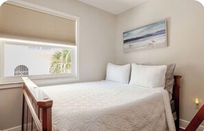 A bedroom with a bed, a window with blinds, a painting on the wall, and a nightlight. - Little Bit of Paradise, Direct Beachfront, Stunning Sunsets, Sleeps 6 (Clearwater)