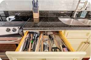 A kitchen with a drawer containing various utensils, a stove, and a sink. - Little Bit of Paradise, Direct Beachfront, Stunning Sunsets, Sleeps 6 (Clearwater)