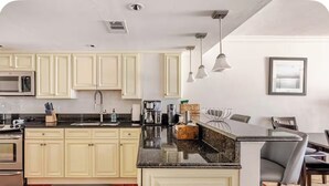 A modern kitchen with cream-colored cabinets, a granite countertop, and stainless steel appliances. - Little Bit of Paradise, Direct Beachfront, Stunning Sunsets, Sleeps 6 (Clearwater)