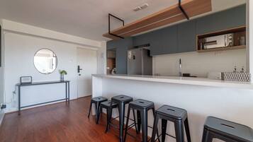 Cozinha moderna com ilha central, banquetas e luminária pendente.