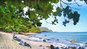 A beach with sand, rocks, and trees. - Front row for Bali Hai and  BEST sunsets on Kauai  @ Pali Ke Kua (Princeville)