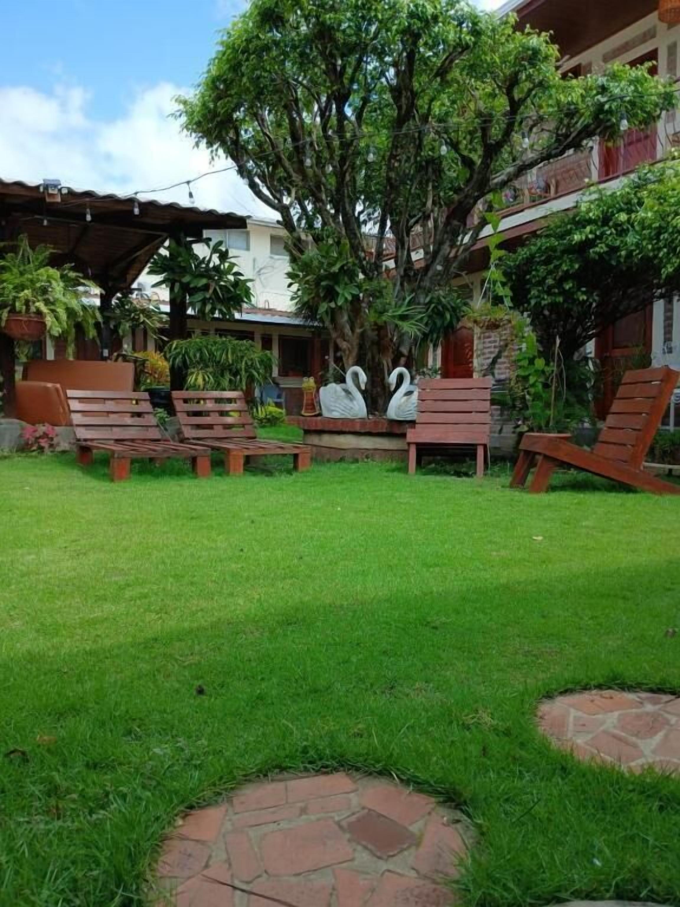 A well-maintained garden with a lawn, stone pathway, and wooden chairs.
