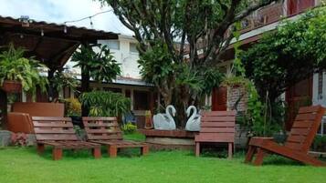 A well-maintained garden with a lawn, stone pathway, and wooden chairs.