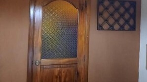 A wooden door with a frosted glass panel, an air conditioning unit mounted on the wall, and a decorative lattice panel above the door. - Hostal Don Miguel (Rivas)