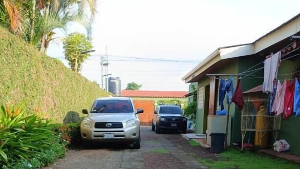 A paved driveway leading to a building with a car parked in front. - Hostal Don Miguel (Rivas)