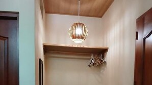 A hallway with a bench, a hanging light fixture, and a door. - Hostal Don Miguel (Rivas)