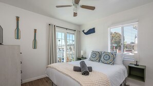 Una camera da letto con un letto, una ventola a soffitto, una finestra con persiane e decorazioni murali.