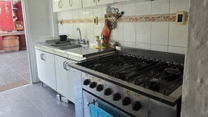 Et køkken med hvide skabe, en gasblus og et flisebeklædt backsplash.
