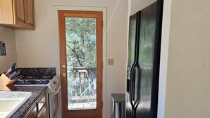 Eine Küche mit Holzausstattung, einem Edelstahlkühlschrank, einem Gasherd und Blick durch eine Glastür.
