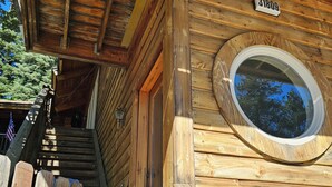 Eine Holzhütte mit einem Rundfenster, einer Holztreppe und einer Tür mit der Nummer 31809.