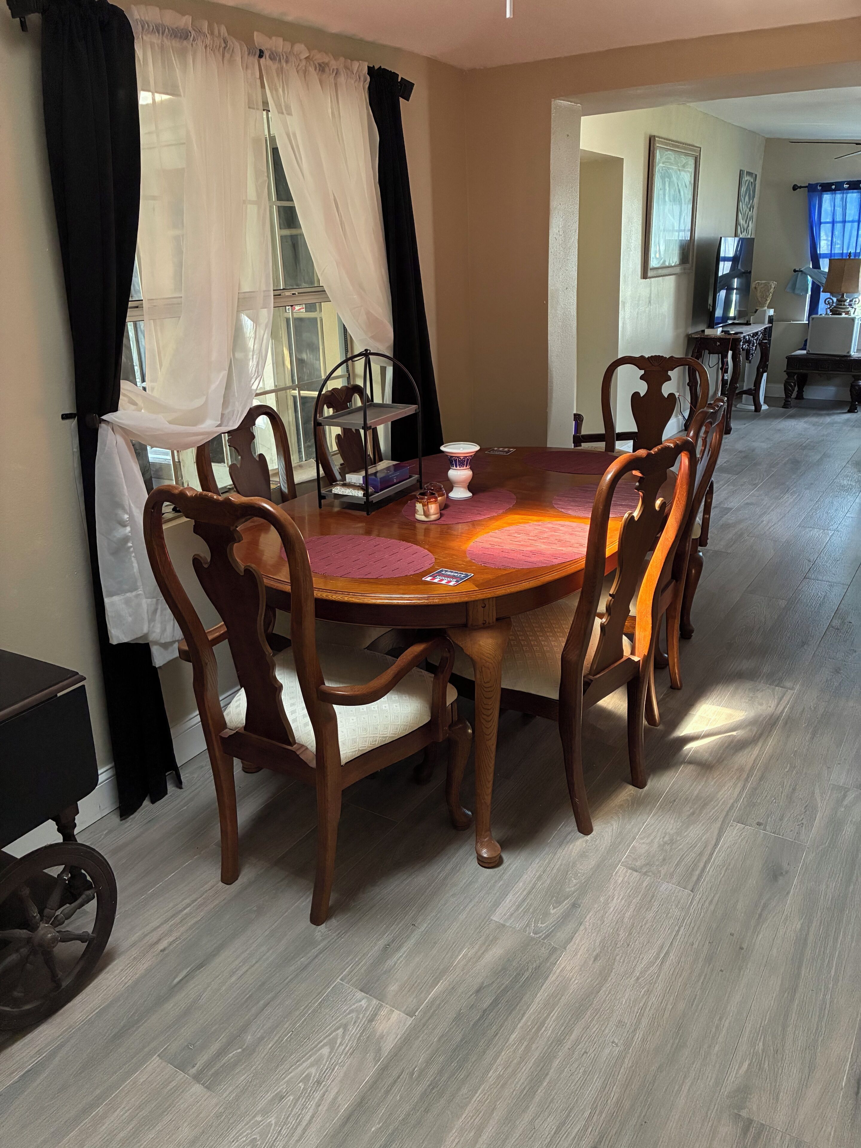 Un coin repas avec une table ronde en bois, six chaises et un lustre.