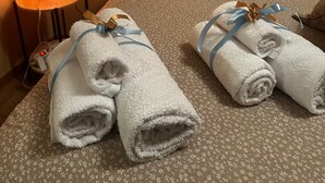 Ett hotellrum med en säng, kuddar, en sänglampa och två handdukar med band.
