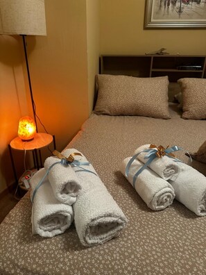 Ein Hotelzimmer mit einem Bett, Kissen, einer Nachttischlampe und zwei Handtüchern mit Schleifen.
