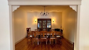 Uma sala de jantar com uma mesa e cadeiras de madeira, um candelabro e arandelas.