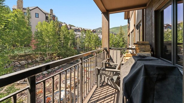Un balcón con vistas a una zona residencial, una terraza de madera y un espacio de estar techado.