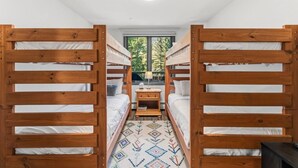 Habitación con literas, una ventana, una mesita pequeña y un tapete estampado.