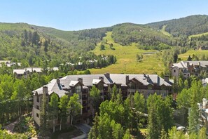 A residential area with multiple two-story buildings, surrounded by lush green hills and trees. - Ski-in ski-out Beaver Creek W/pool and hot tub (Beaver Creek)
