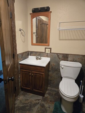 Een badkamer met een houten wastafelmeubel, een witte wastafel, spiegel en een wit toilet.