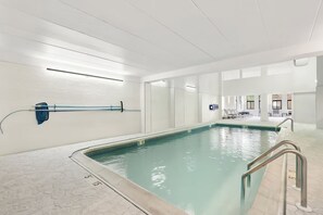 Una piscina con agua cristalina, un toallero azul y suelo de baldosas.