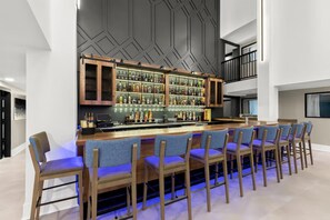 Eine Bar mit langer Theke, verschiedenen Sitzmöglichkeiten und einem modernen, geometrischen Wanddesign.