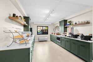 Una cocina moderna con armarios verdes, horno empotrado y ventana con vistas.