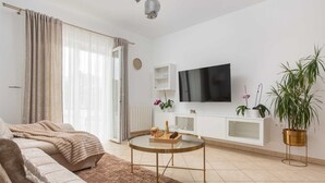 Ein modernes Wohnzimmer mit einer Couch, einem Couchtisch, einem Fernseher und Topfpflanzen.
