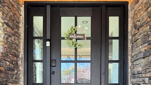 A black door with a 'welcome' sign, a doormat, and a view of the outside. - Entire Downtown Home - Yellowstone and Teton Base (Idaho Falls)