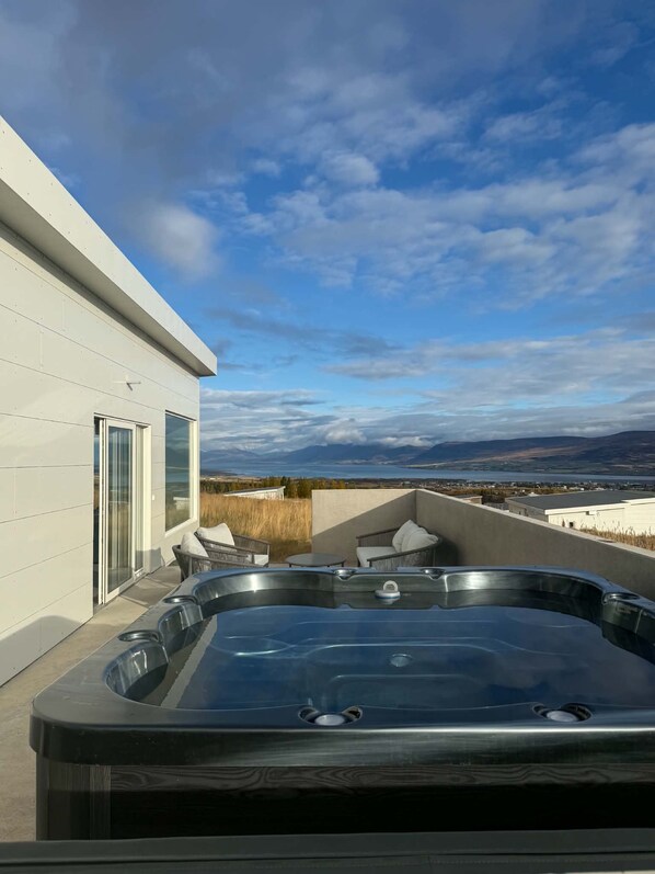 A hot tub on a rooftop with a view of mountains and a body of water.
