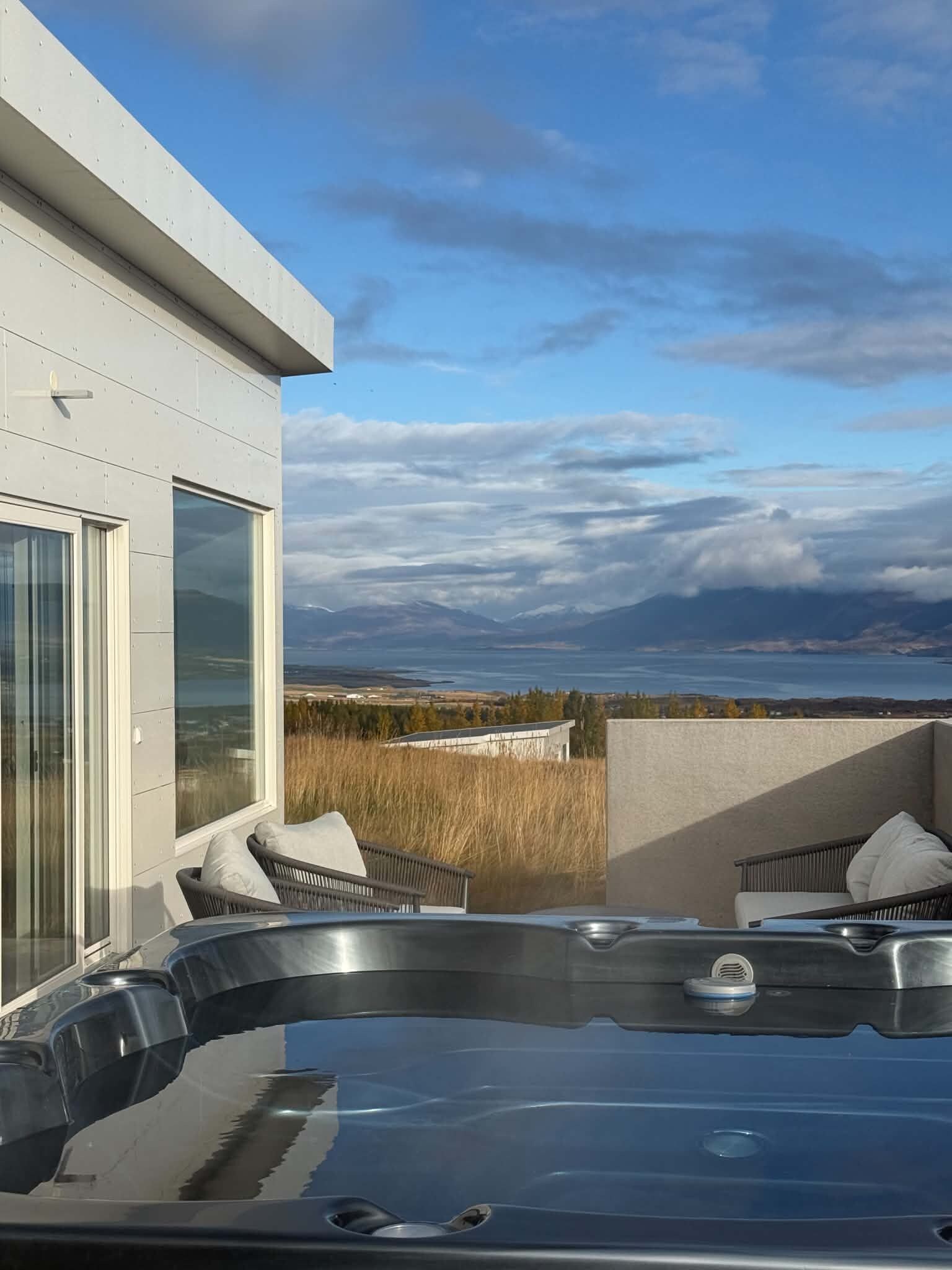 A modern building with a hot tub and outdoor seating area, overlooking a scenic landscape.