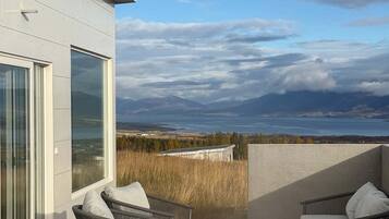 A modern building with a hot tub and outdoor seating area, overlooking a scenic landscape.