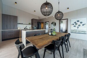 A modern kitchen with dark wood cabinets, a wooden dining table, and black chairs. - Design House in Akureyri – Private Hot Tub, Sea & Mountain Views, 2 bathrooms (Akureyri)